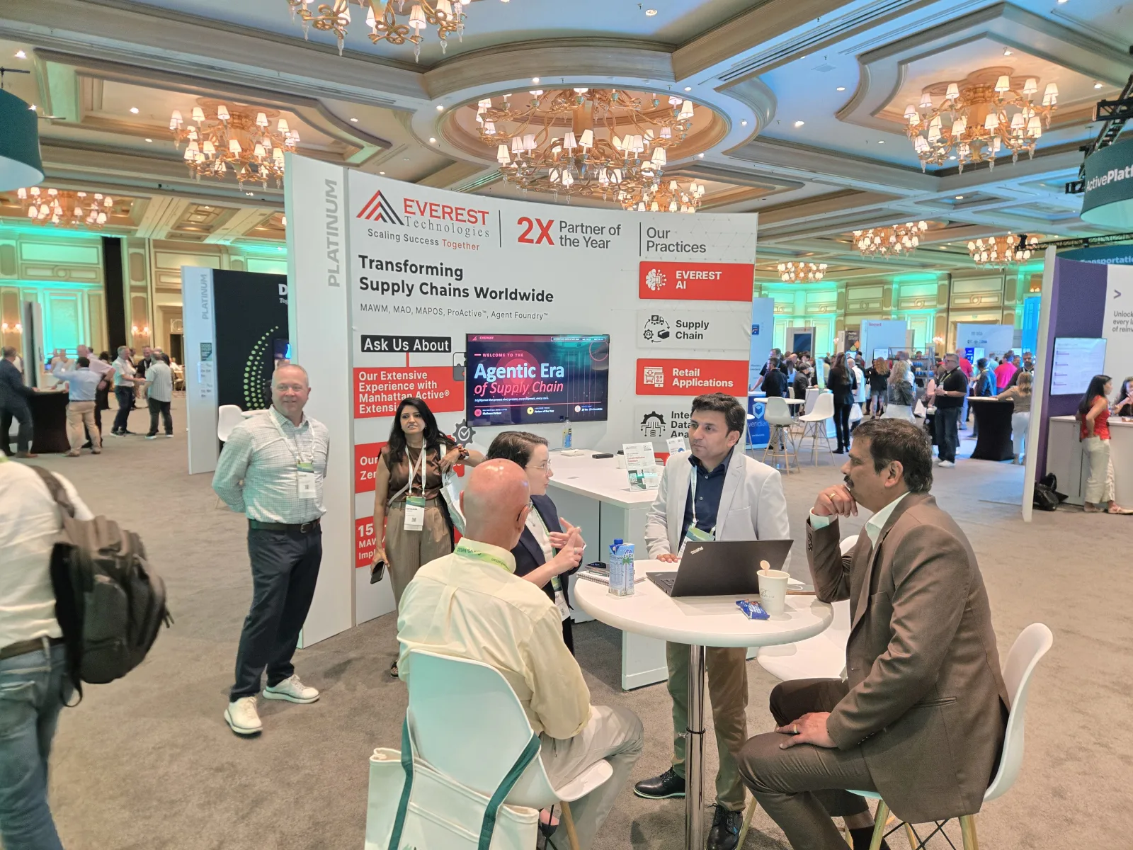 Everest Technologies booth with the "Transforming Supply Chains Worldwide" wall and the team in a customer meeting