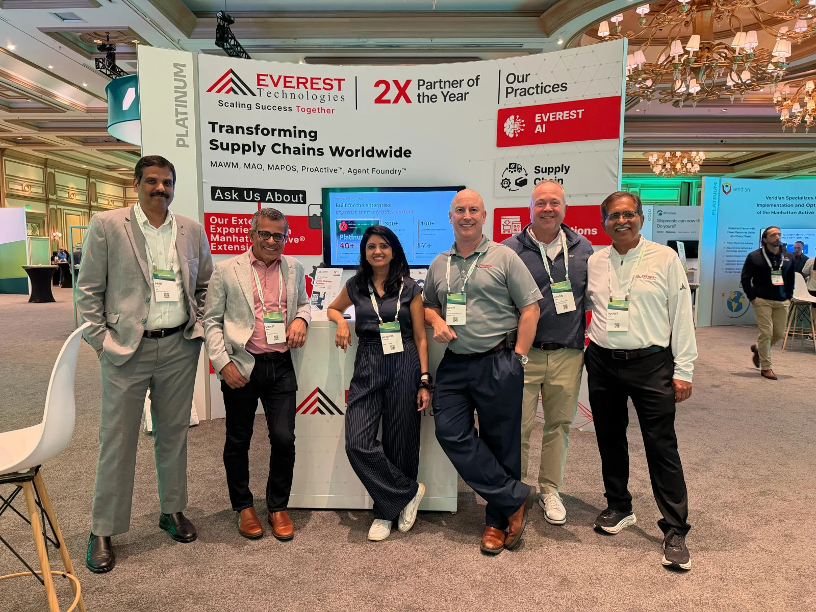 Everest Technologies leadership team posing in front of the Platinum Partner booth at Manhattan Momentum 2026